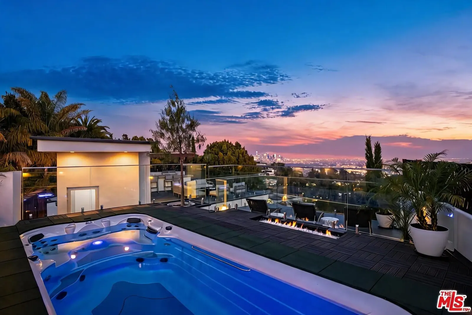 Infinity-edge pool and spa with fire feature overlooking Los Angeles at twilight