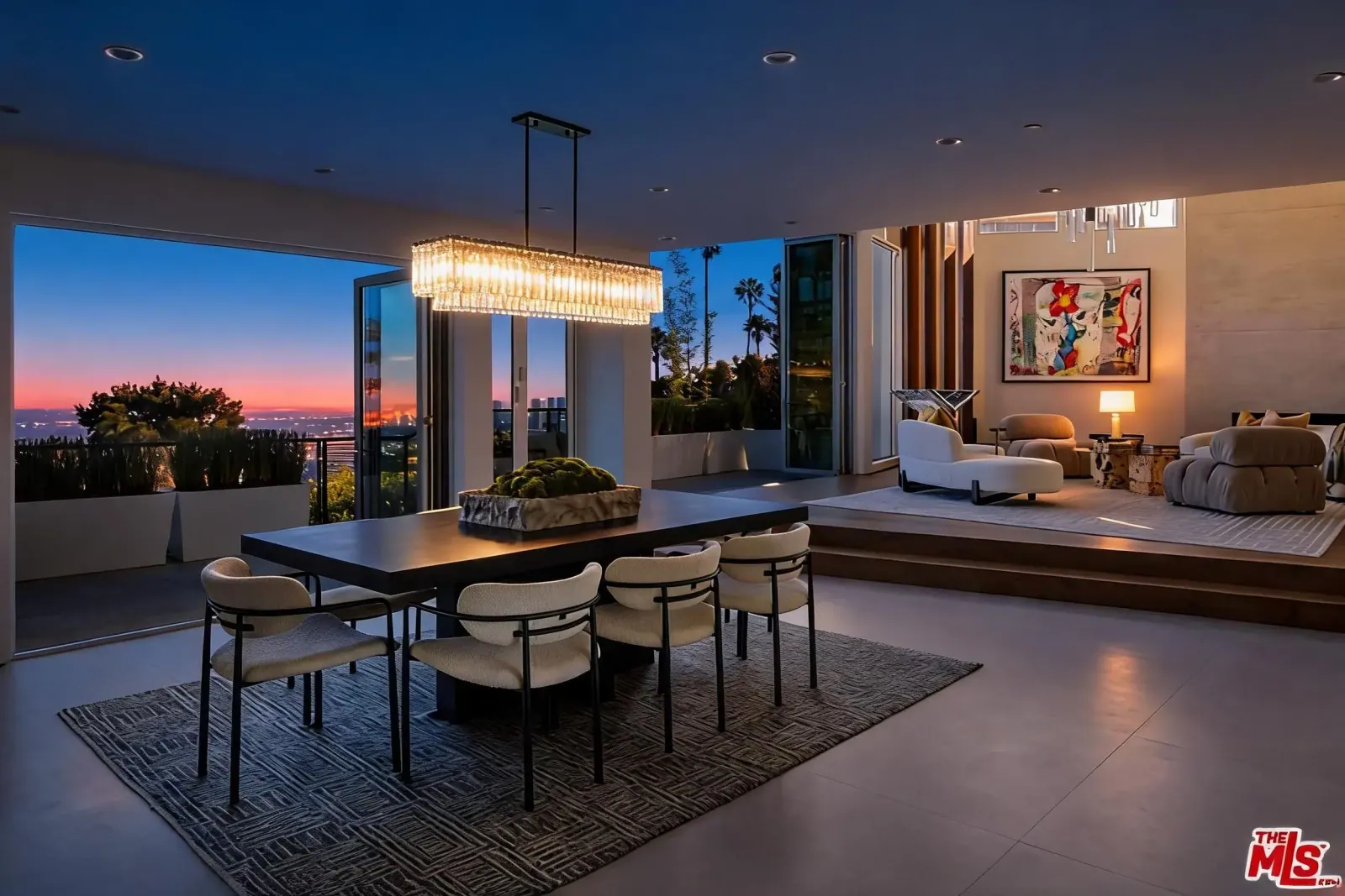 Dining table beneath a crystal chandelier with terrace doors open