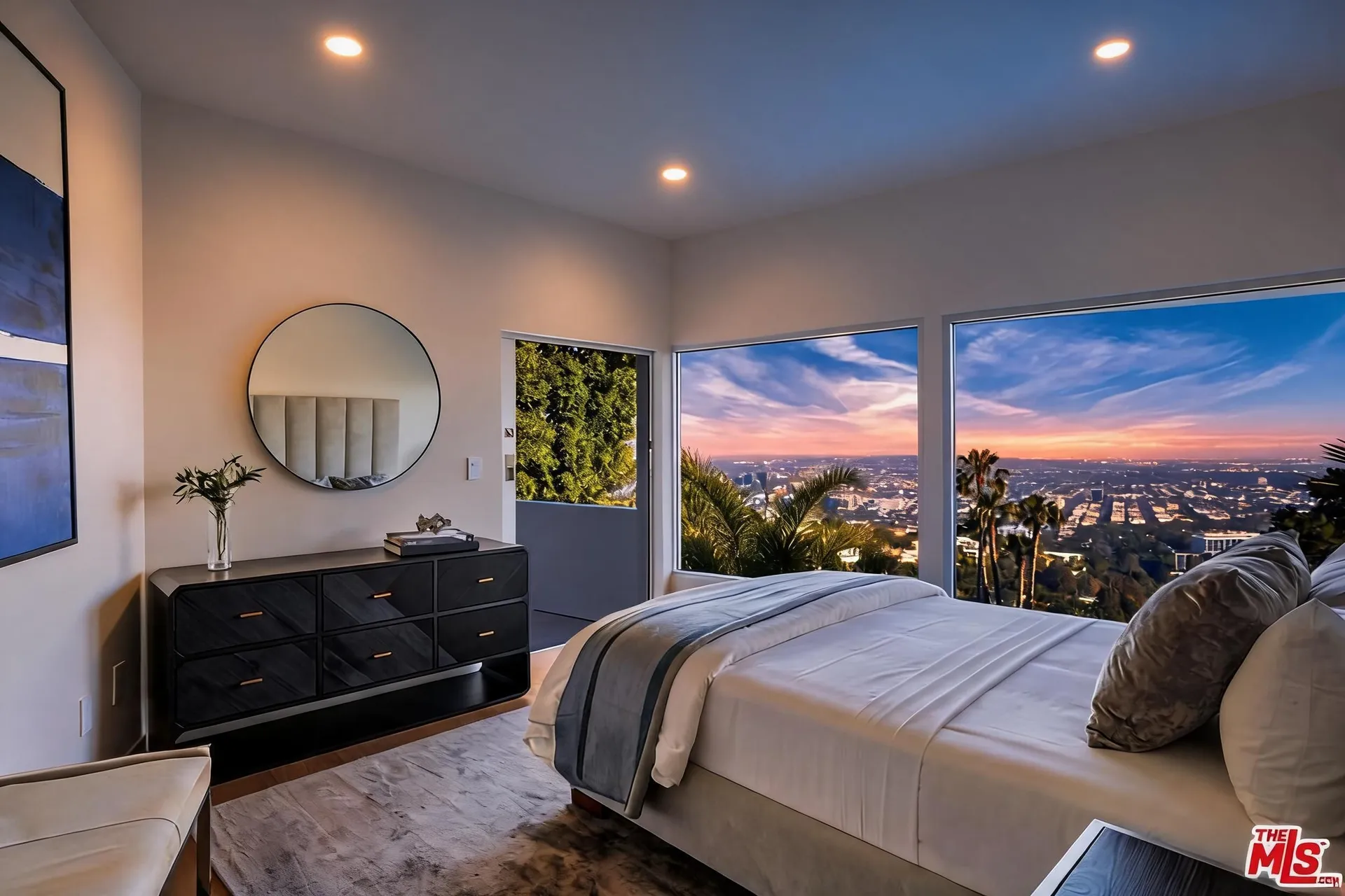 Guest suite with upholstered bed, dark wood dresser and city view